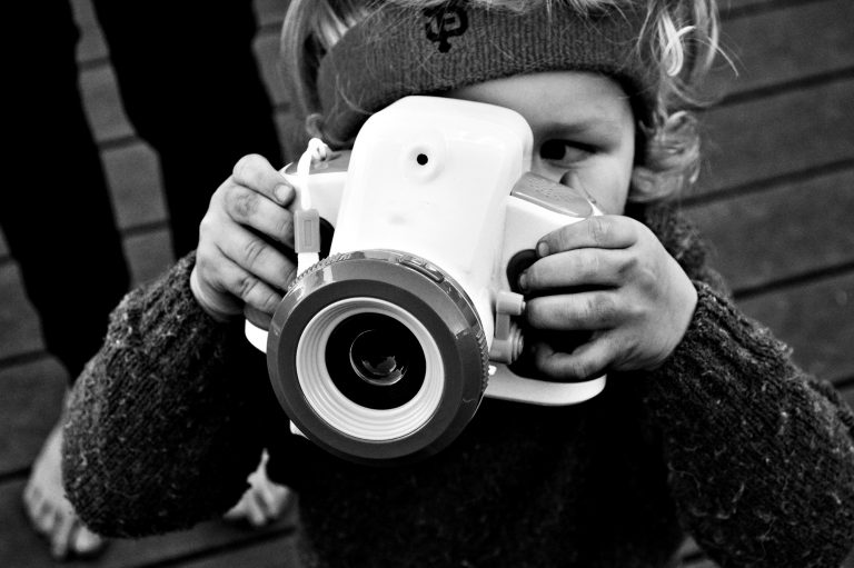 Black and white photo of a boy taking a picture with a toy camera