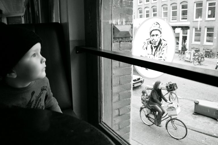Boy looking out the window of a cafe in Amsterdam, black and white photo