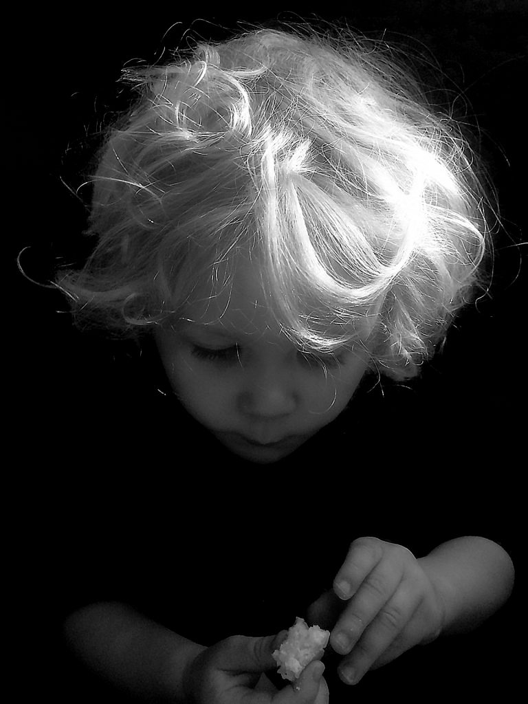 Black and white photo of a boy eating a pancake