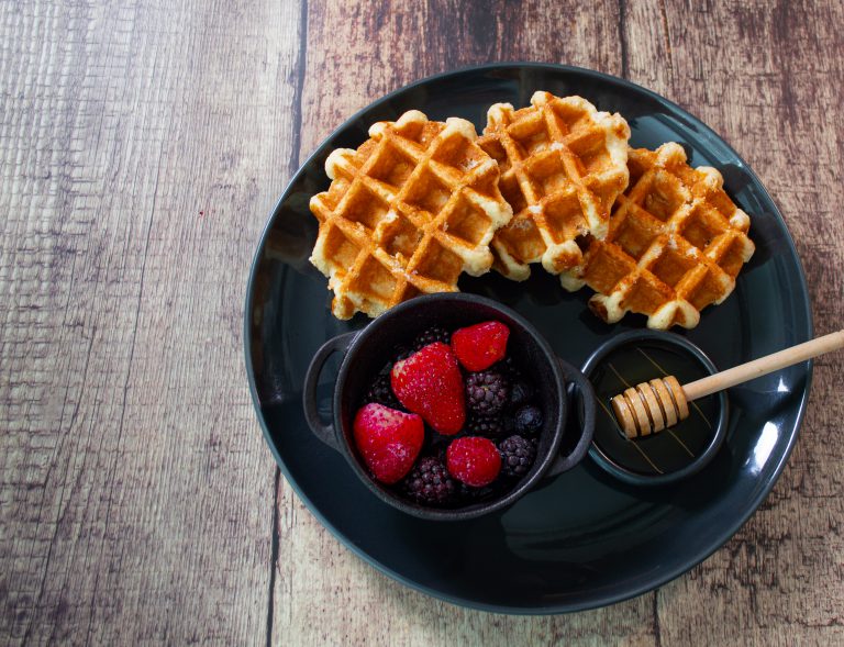 Waffels with honey and berries on the side plated and on a wood table